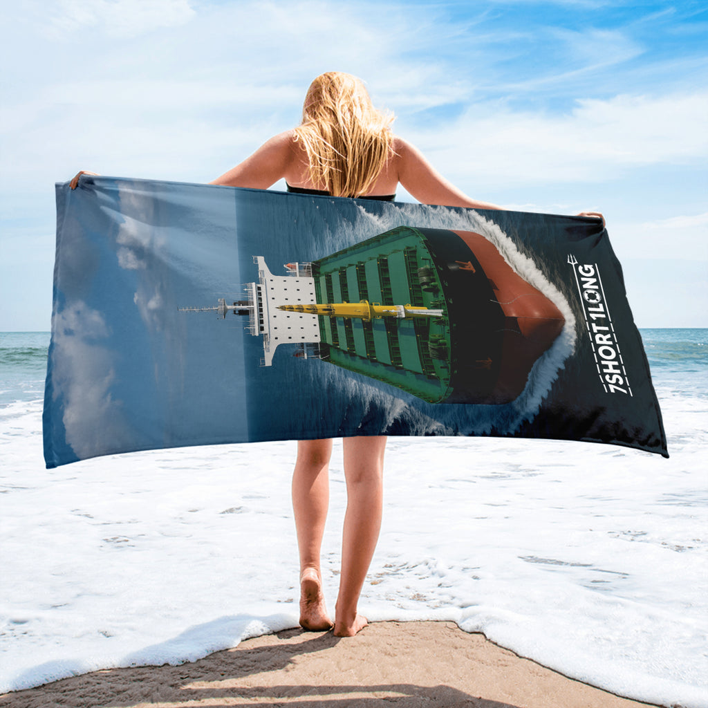 Crew member holding a beach towel with a graphic design on a beach