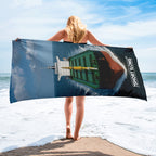 Crew member holding a beach towel with a graphic design on a beach